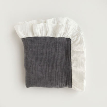 A folded muslin baby blanket or swaddle in dark gray and white, featuring a ruffled edge, photographed on a clean off-white background.