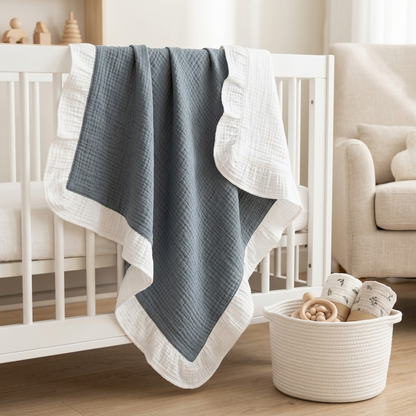 A baby blanket with a textured grey center and a white ruffled border, draped over a white crib in a softly lit nursery.